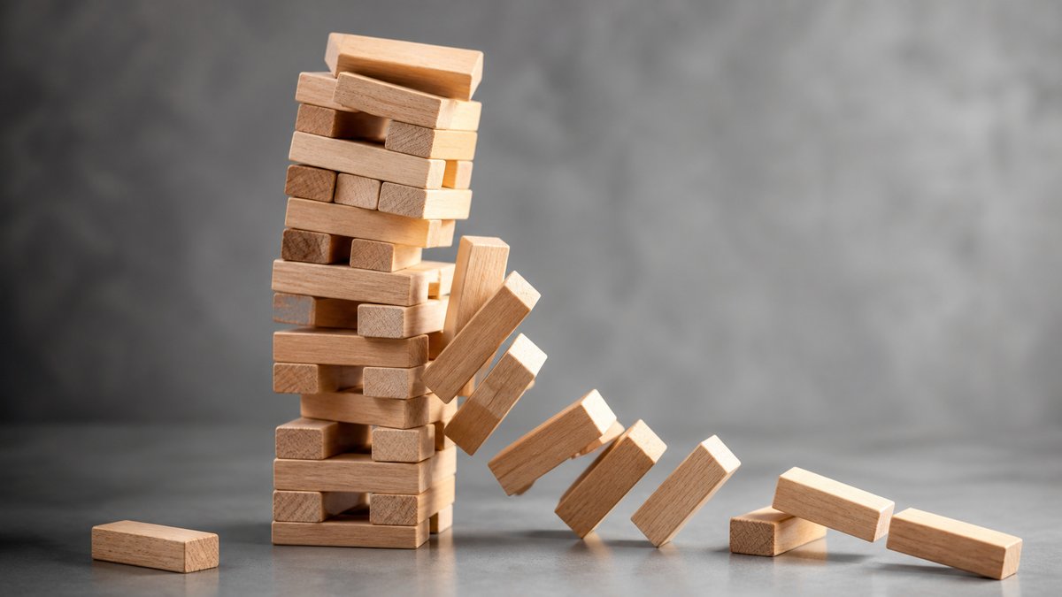 Jenga tower with one block removed causing several blocks to fall, domino effect concept, NO text, N